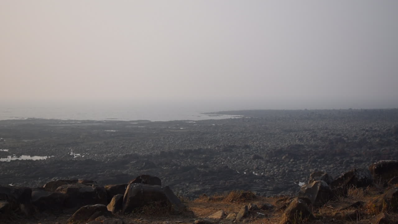 A Young Indian athlete jogging and stopped on mountain cliff near a ocean and enjoying view and weather after getting tired, video background in Prores 422 HQ