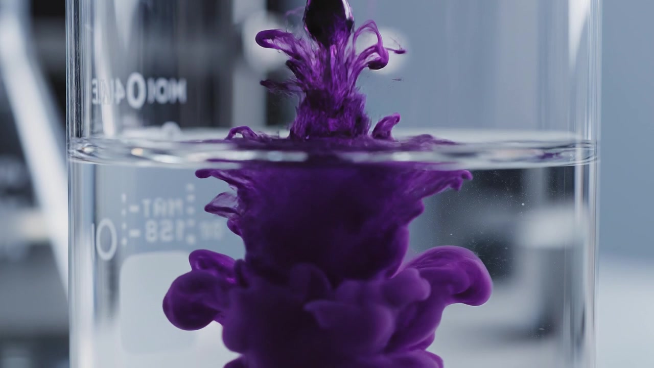 Purple Liquid Drop Falling into a Clear Glass Lab Beaker
