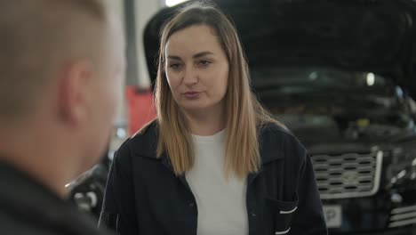 female manager discussing vehicle repair with mechanic in auto repair shop