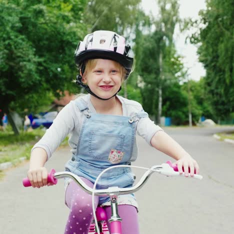 a blonde girl in a helmet riding a bike on the street