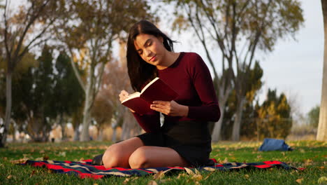 una hermosa joven estudiante leyendo un libro o una novela al aire libre en un campus escolar antes de que la clase se deslice hacia la izquierda