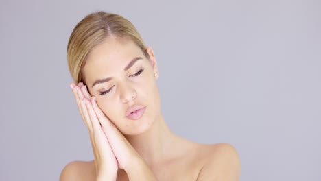 pretty young blond woman making a sleep gesture