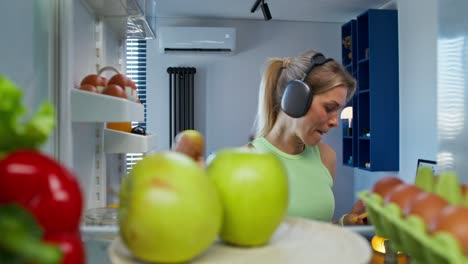 mujer tomando frutas y verduras del refrigerador