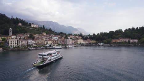 Pontoon-Ferry-Boat-Traveling-across-Lake-Como-to-Touristic-Bellagio-Town,-Aerial