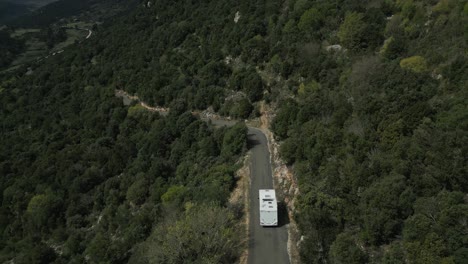 Camper-Van-Drives-Through-Steep-Hills-of-Southern-France,-Wooded-Forest,-Aerial-Drone-Shot,-Aude-Department