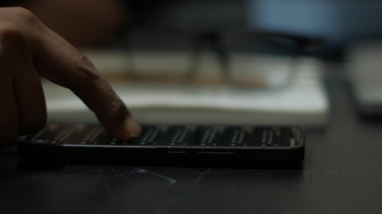 Persona che scorre lo smartphone alla scrivania