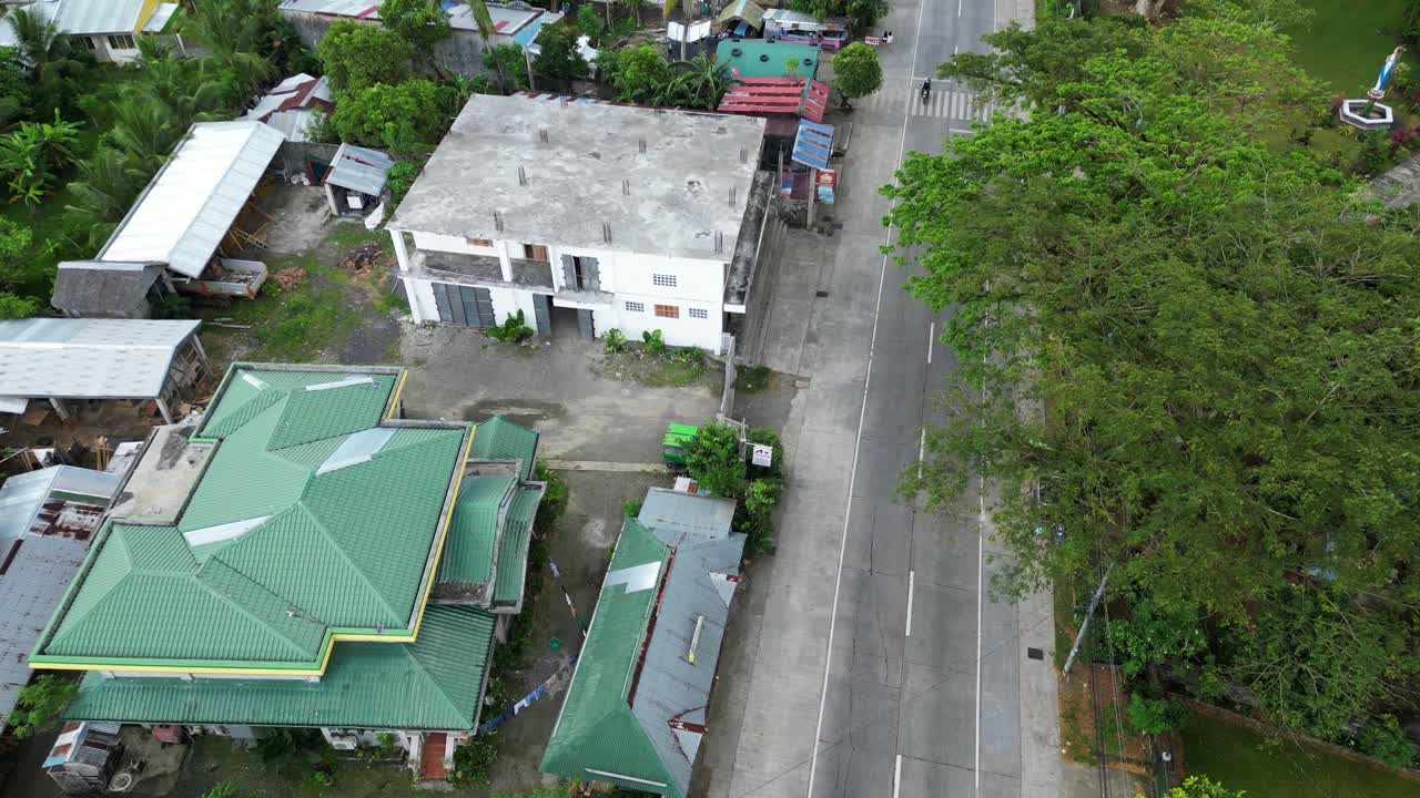 Bird's eye Flyover Shot of developing impoverished Asian Town Village with tropical greenery and nearby mopeds driving