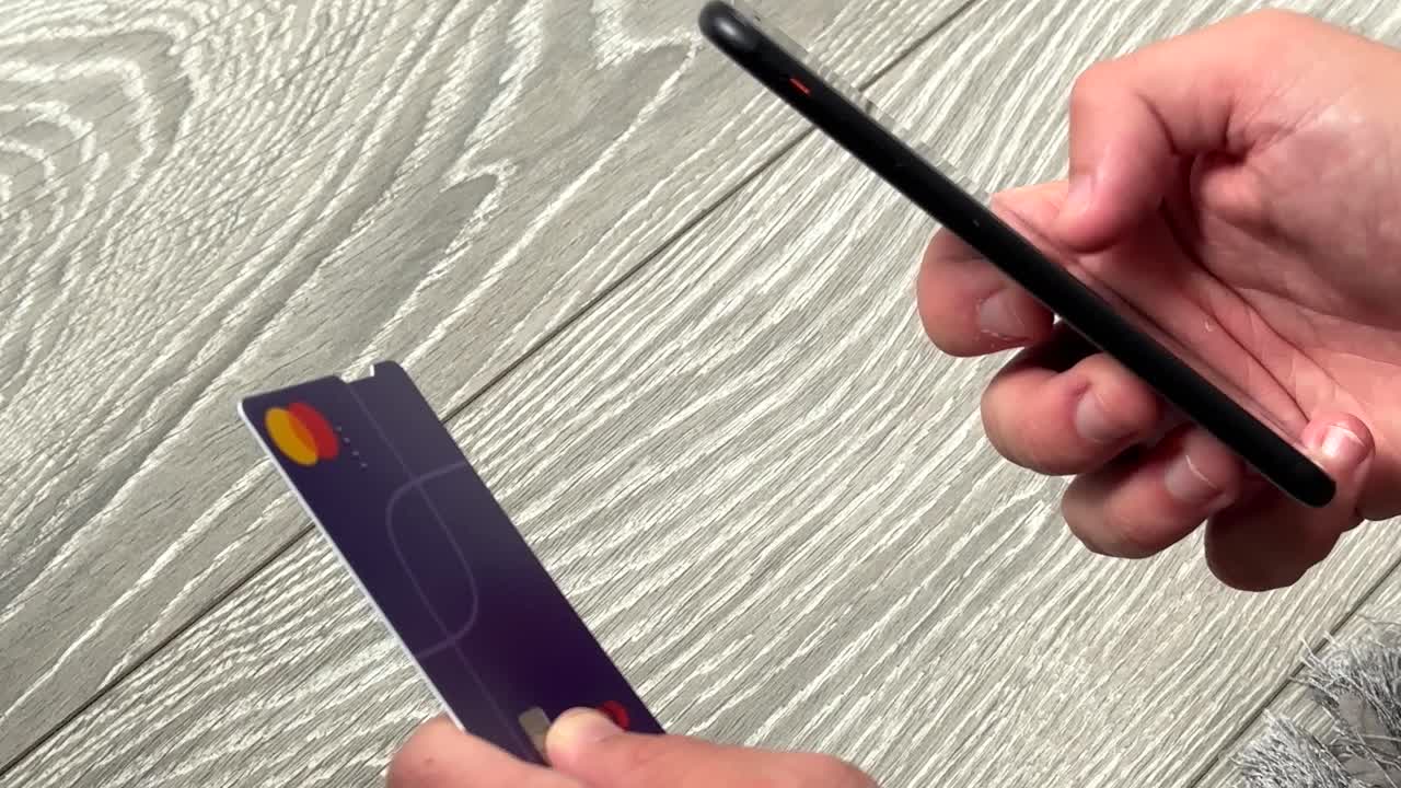 Person Using Smartphone in One Hand and Credit Card in the Other Making Online Purchase