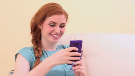 beautiful brunette sitting on couch using smartphone