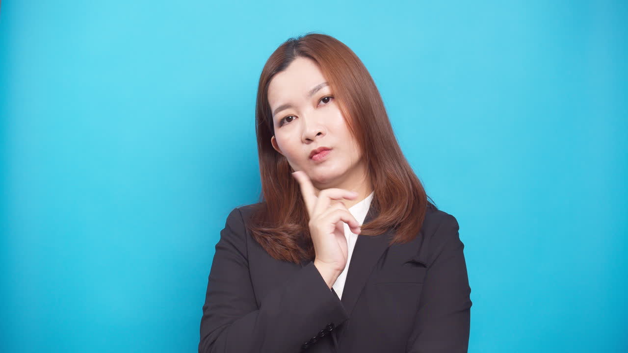 불확실한 젊은 여성 사업가가 생각하고 파란색 배경 위에 고립된 아이디어 계몽을 바라보고 있습니다.