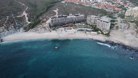 aerial shot from a beautiful hotel overlooking the multi-story building, swimming pools and vacationers at the cape thompson hotel in los cabos on monument beach with blue sea during a mexico vacation