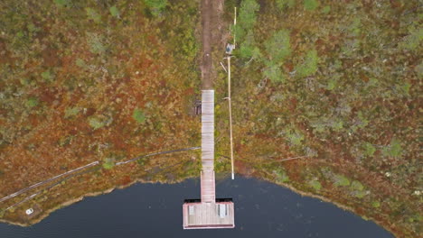 bird's eye view of a wooden pier on black lake in autumn forest of sweden