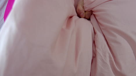 a close-up on the hand of a young woman as she crushes and crumples a pillow, sheets in ecstasy the moment of orgasm while having sex