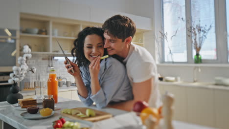 una pareja encantadora abrazándose en la cocina preparando el desayuno juntos en el primer plano de la cocina.