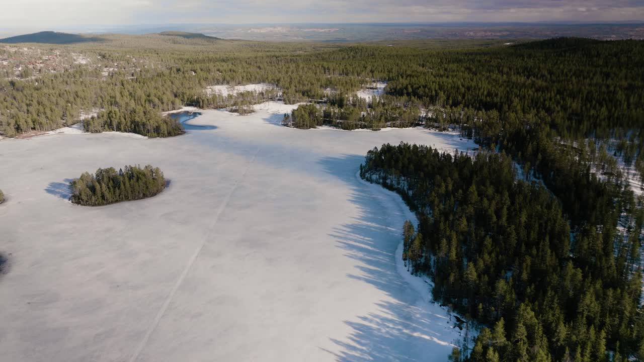 Drone ascend and tilt over frozen lake and forest in Sweden
