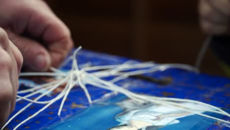 hands tying the treads of a blue giftbox