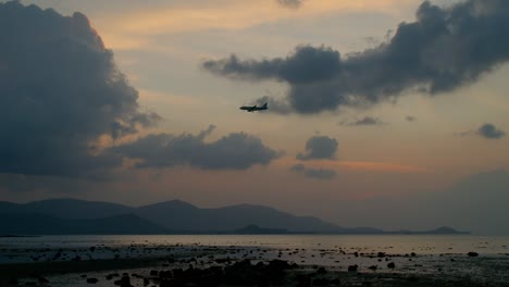 airplane landing over coastal sunset