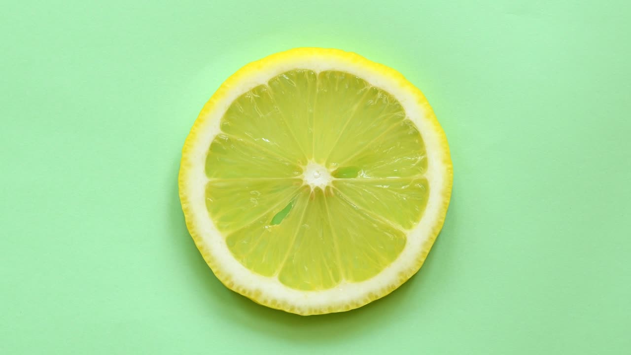 una rebanada de limón girando vista superior en fondo verde