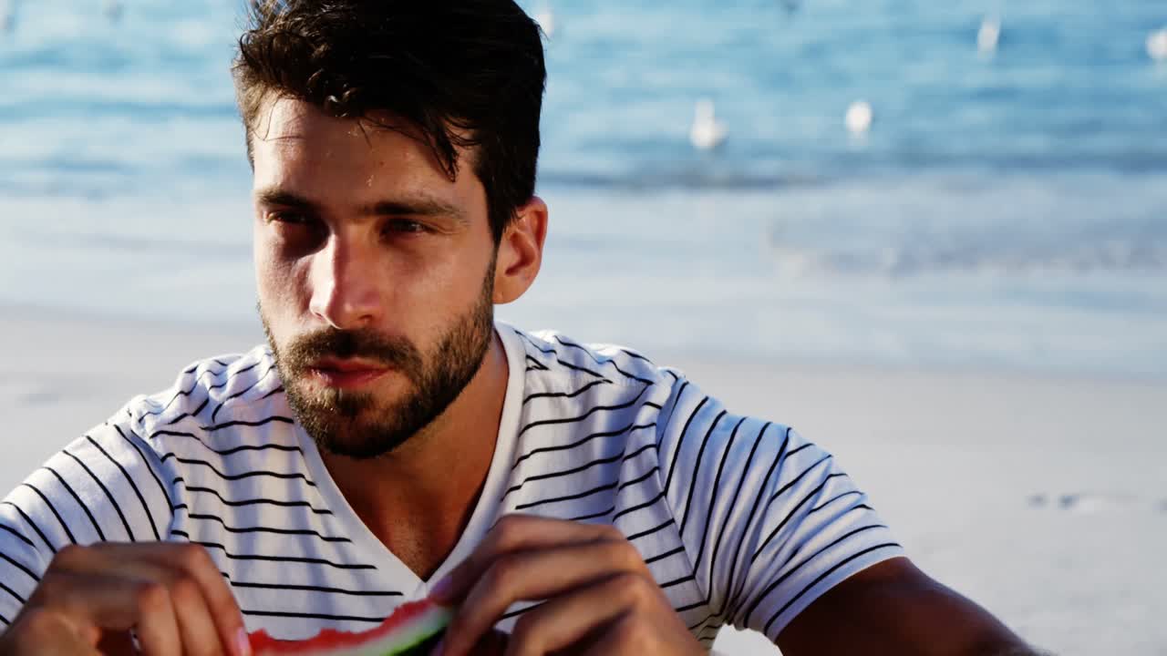 hombre con sandía en la playa 4k