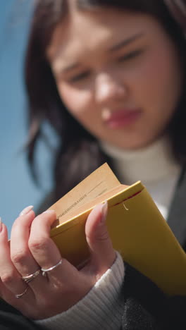 반지로 장식된 잘 은 손을 가진 학생의 클로즈업, 노란색 표지 책의 페이지를 사려 깊게 읽고 관찰하고, 밝은 빛 아래 야외를 상합니다.