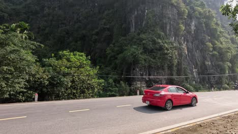 red car travels along a mountainous road