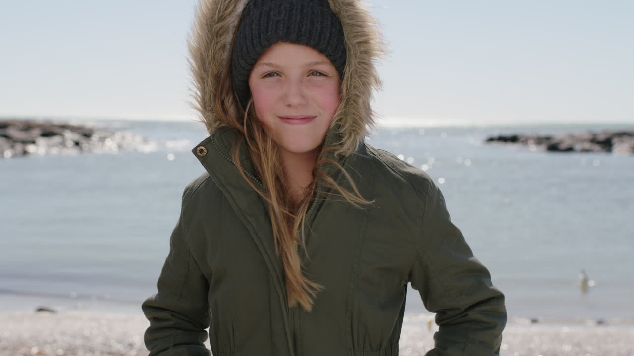 chica en la playa sonriendo retrato feliz de un niño vestido cálido con sombrero de gorra y abrigo