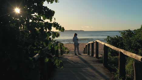 woman stands on wooden deck using smartphone with running suit and sneakers