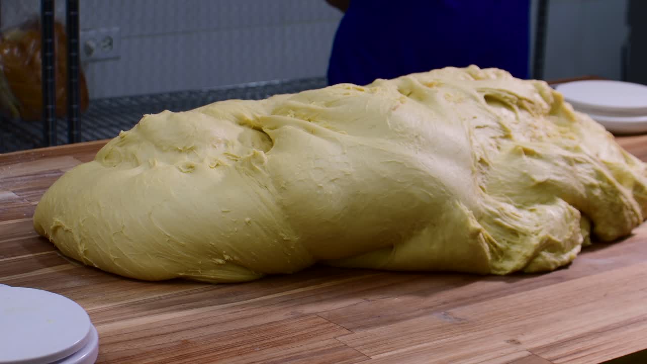Large dough on table, ready for kneading, teamwork in kitchen setting