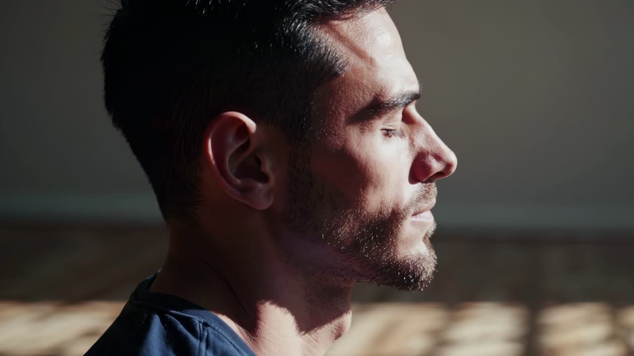 Side profile video of a man meditating in soft sunlight. Captured at eye level, the serene setting