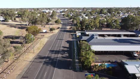 drone ascendiendo sobre una carretera principal en una ciudad de campo y un motel cerca de la carretera con paneles solares en el techo
