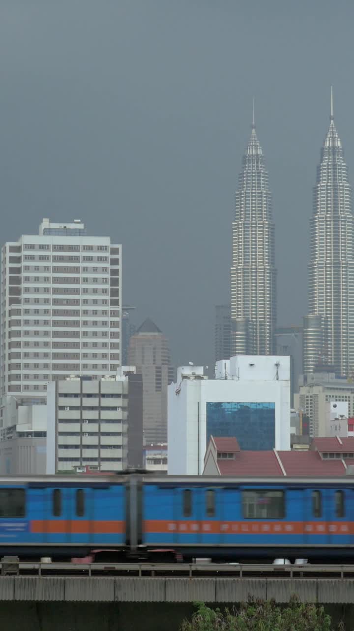 Treno che passa accanto allo skyline di Kuala Lumpur con le Petronas Twin Towers