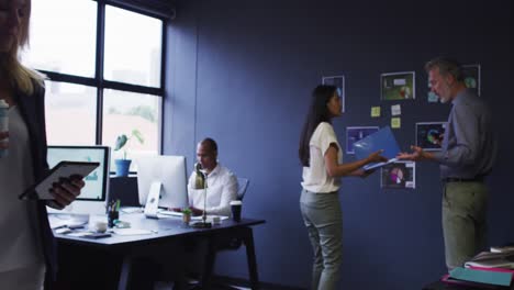 diverse business colleagues using computers and talking in office