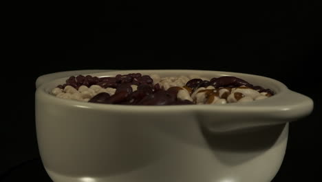 vista lateral de primer plano: un cuenco de frijoles secos gira sobre un fondo oscuro