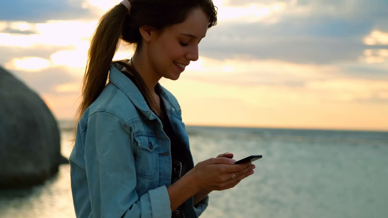 mujer usando teléfono móvil en la playa 4k