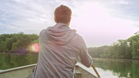 man paddles boat on calm water