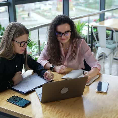 business discussion between two colleagues sitting at the table in front of laptop. comfortable working place in a large office