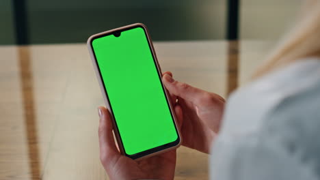 Woman-hand-scrolling-green-phone-screen-indoor-closeup.-Lady-reading-cellphone