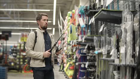 hombre comprando cañas de pescar en una tienda de artículos deportivos