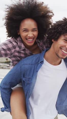 video vertical de una feliz pareja biracial divirtiéndose en el paseo marítimo