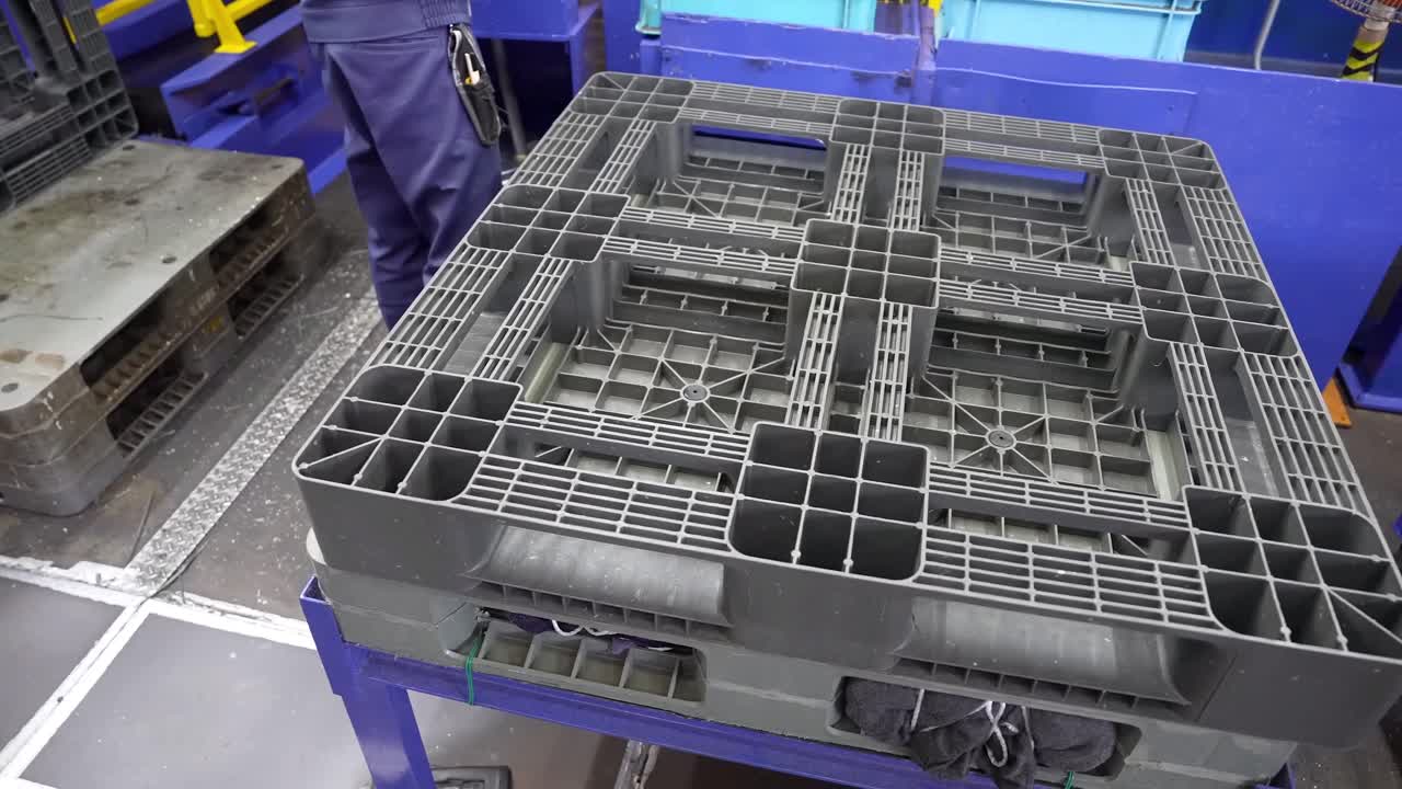 Factory Worker Handling Recycled Plastic Pallets.