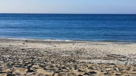 Beach-and-sea-with-gentle-waes,-at-New-Quay,-Ceredigion,-Wales,-UK