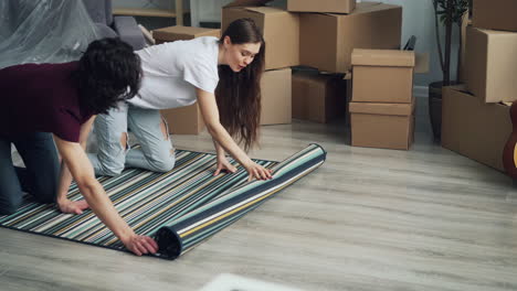 couple unrolling carpet in new home