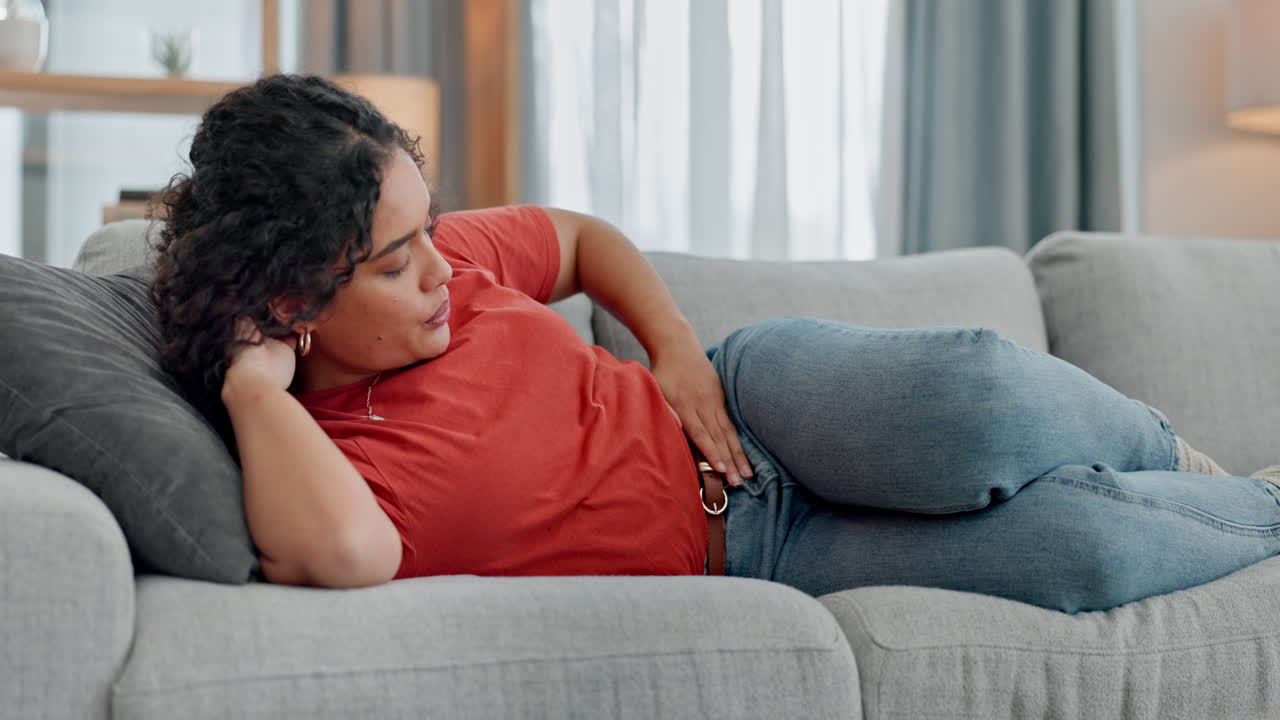 dolor de estómago, ansiedad y mujer en un sofá