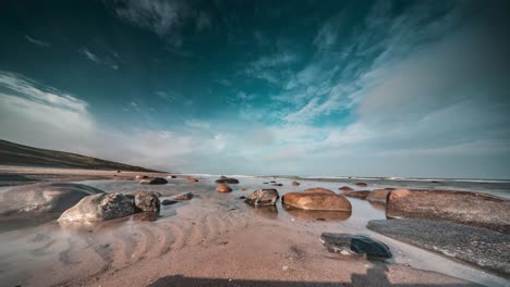 Nubes-Blancas-Claras-Vuelan-Sobre-La-Playa-Rocosa-Mientras-Las-Olas-Ruedan-Lentamente-Sobre-Las-Piedras