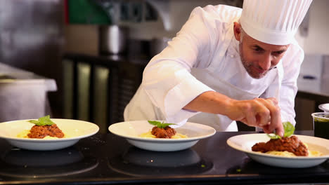 Chef-garnishing-pasta-dish-with-basil-leaf