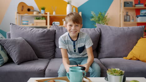 smiling boy playing video games on a couch