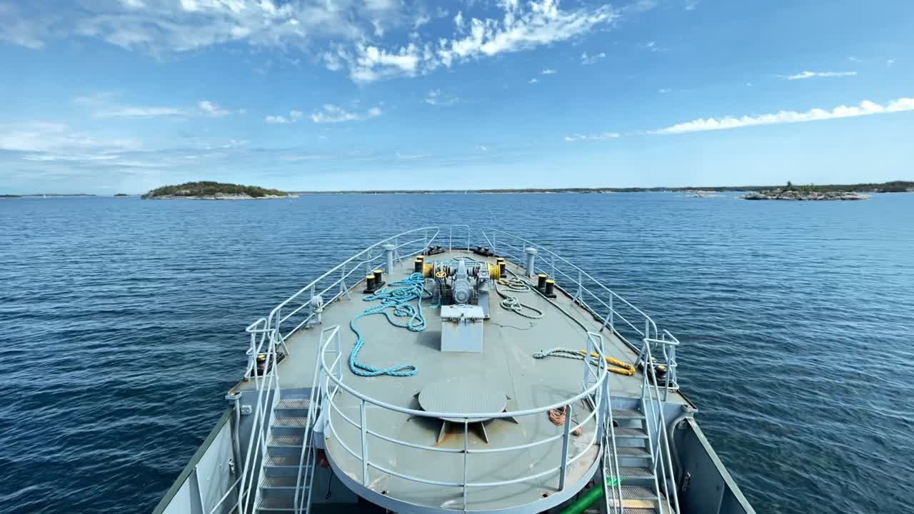 Schleppboot fährt an einem Sommertag durch eine schmale Fahrrinne im finnischen Schärengarten