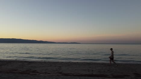 Man-walking-at-the-beach-in-the-morning-during-sunrise