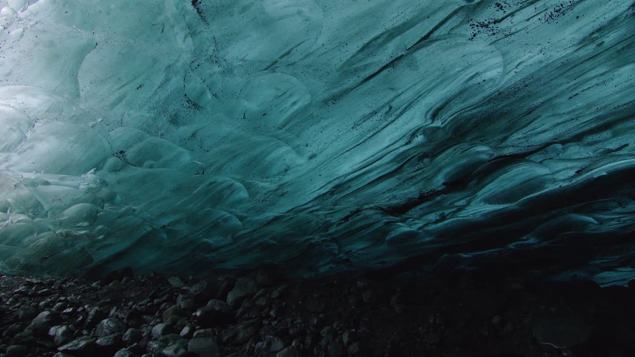 Under the ice cover of the glacier in Iceland between blue ice and black stones
