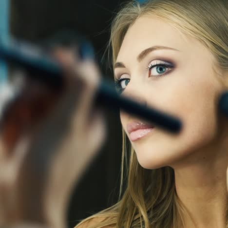 Attractive-woman-corrects-makeup-in-front-of-the-mirror